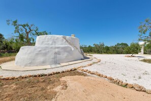 A white, multi-tiered structure with a chimney, surrounded by gravel and sparse vegetation. - 3510 Villa Montipuglia by Perle di Puglia (Carovigno)