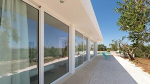 A modern building with large glass windows and a gravel pathway leading to a pool area. - 3510 Villa Montipuglia by Perle di Puglia (Carovigno)