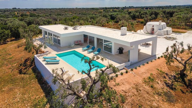 A modern house with a swimming pool, large windows, and a view of the surrounding landscape. - 3510 Villa Montipuglia by Perle di Puglia (Carovigno)