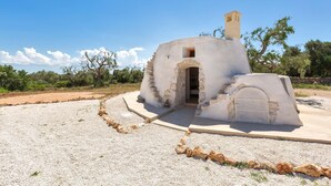 A small, rustic stone building with a chimney, an arched entrance, and a small door. - 3510 Villa Montipuglia by Perle di Puglia (Carovigno)