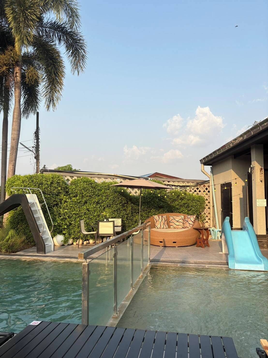 Un área de piscina con tobogán, sillas de descanso y un pequeño espacio de estar al aire libre.
