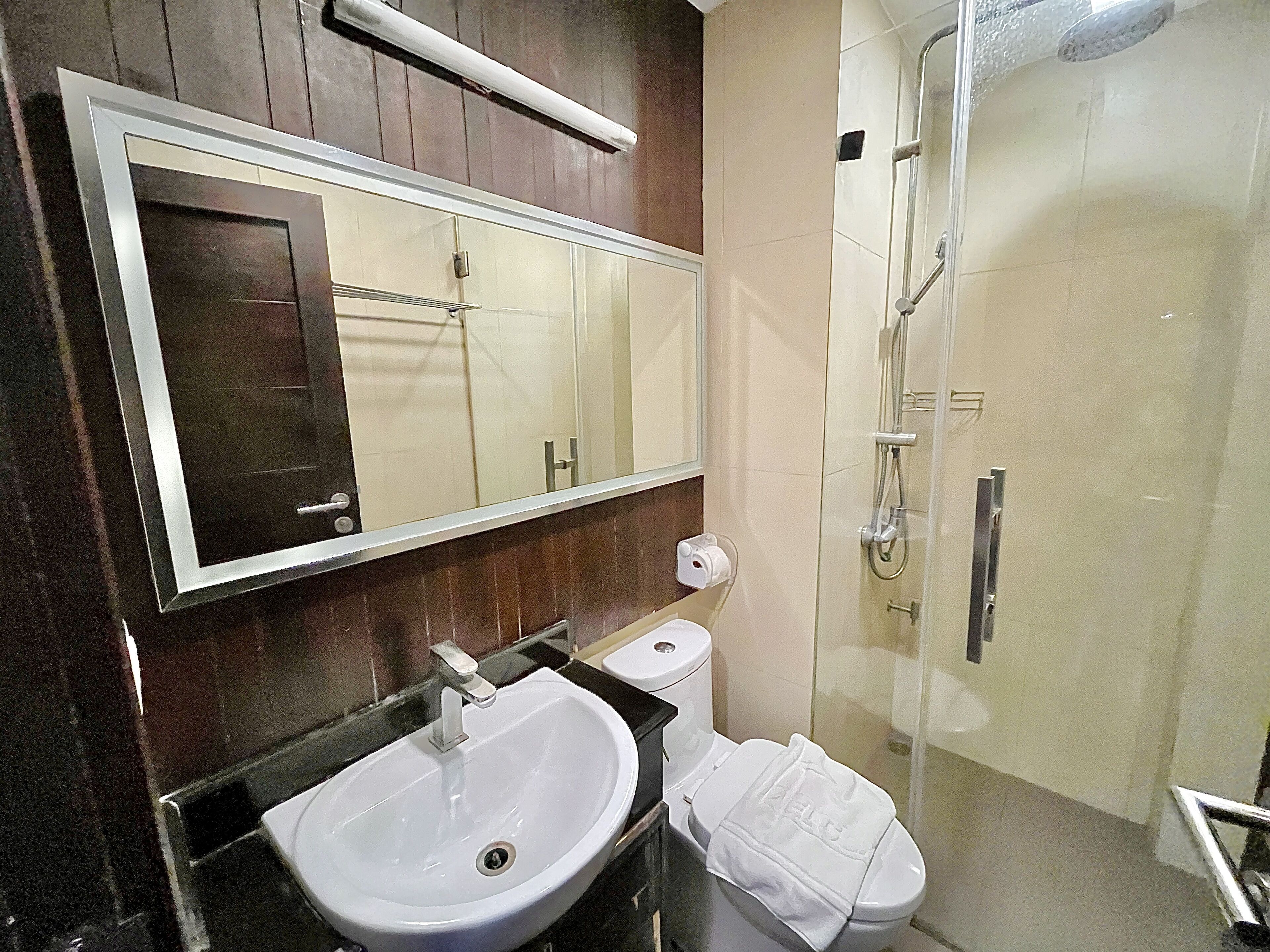 A bathroom with a sink, mirror, toilet, and shower.