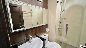 A bathroom with a sink, mirror, toilet, and shower.