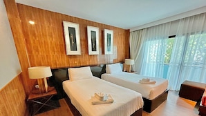 Habitación de hotel con dos camas, paneles de madera en las paredes, cuadros enmarcados y un ventanal con cortinas.