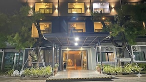 Un hotel con letrero de neón, varias ventanas y un acceso cubierto.