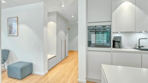 A modern kitchen with white cabinetry, a built-in oven, and a coffee machine.