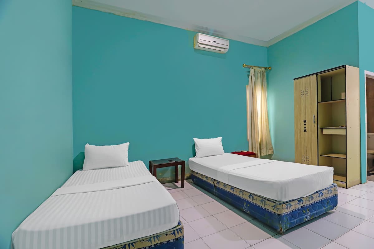 A room with two beds, a wardrobe, and an air conditioning unit.