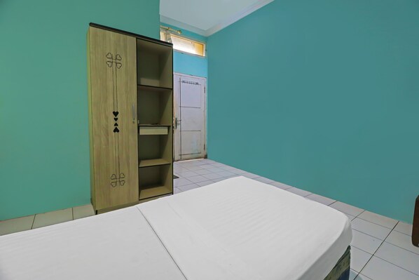 A room with teal walls, a wooden wardrobe with heart designs, a white bed, and a white door. - Hotel O Wisma Permata Syariah (Bangko)
