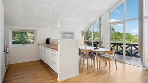 Una cocina moderna con armarios de madera, un lavamanos y un comedor con mesa y sillas.