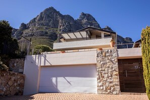 Ein modernes Haus mit Garage, Steinmauer und Blick auf die Berge.