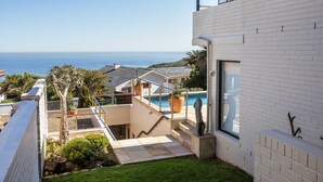 Una casa moderna con piscina, una escalera y vista al océano.