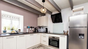A modern kitchen with white cabinets, a stainless steel refrigerator, a microwave, and a coffee maker.