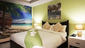 A hotel room with a bed, nightstands, and a wall mural of a beach scene.