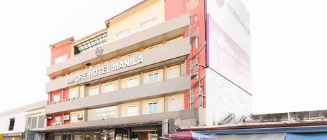 Ein mehrstöckiges Hotel mit einem Schild, auf dem 'AMORE HOTEL MANILA' steht.