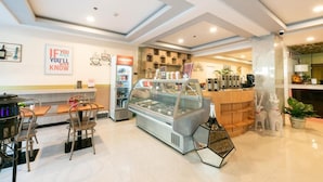 A modern cafe interior with a glass display case, wooden tables, and chairs.
