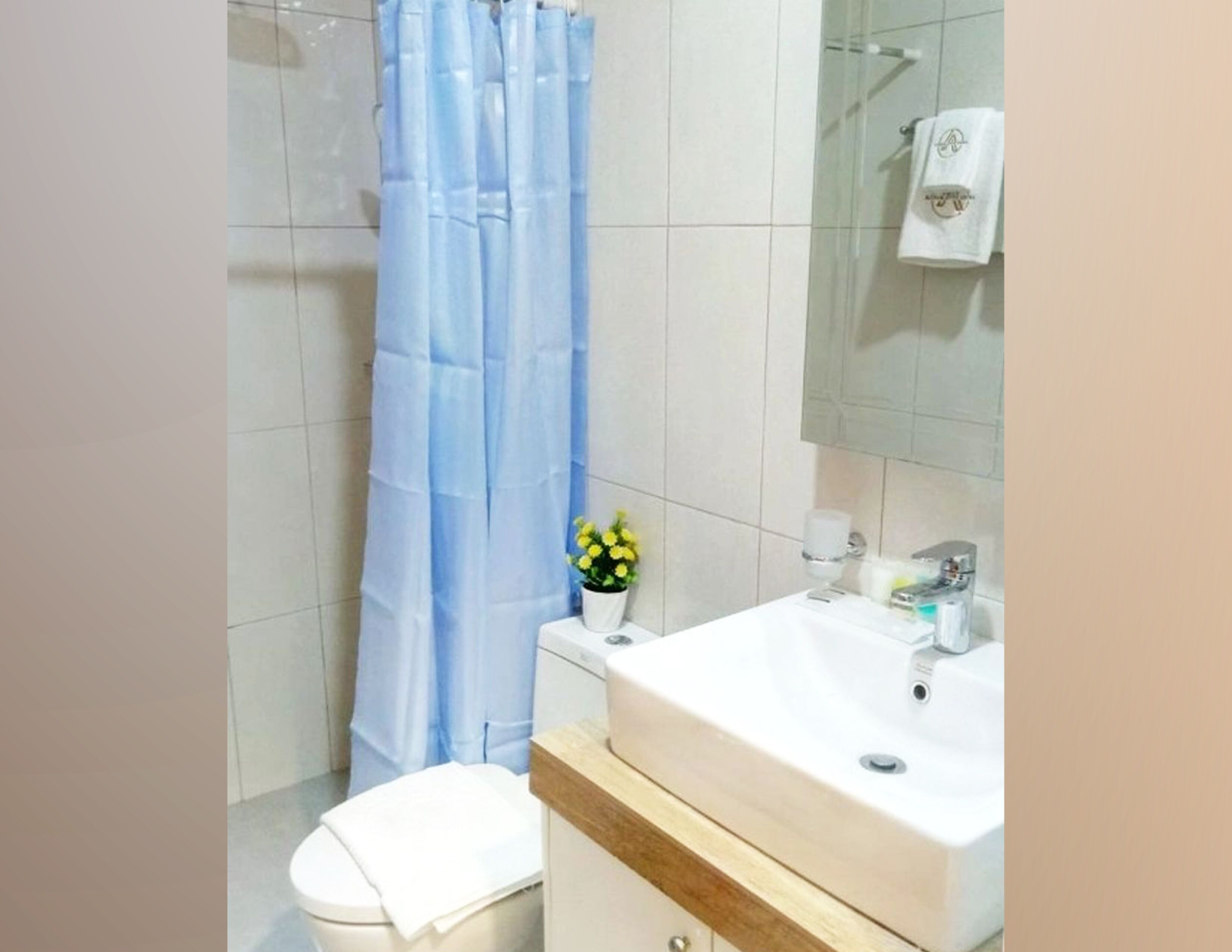 Une salle de bain avec un lavabo blanc, un miroir, un porte-serviettes et un rideau de douche.