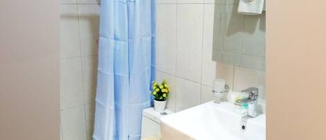 Une salle de bain avec un lavabo blanc, un miroir, un porte-serviettes et un rideau de douche.