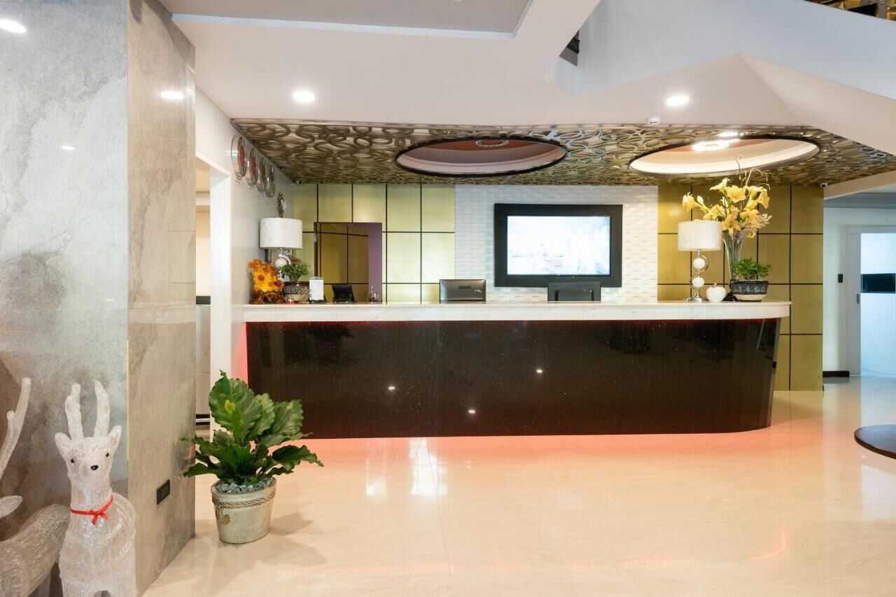 A reception area with a marble reception desk, a flat-screen TV, and a potted plant.