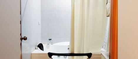 A bathroom with a bathtub, toilet, and shower area.