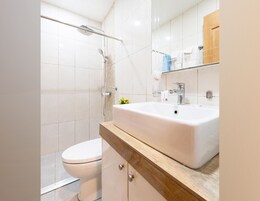 A modern bathroom with a white sink, a toilet, and a shower.