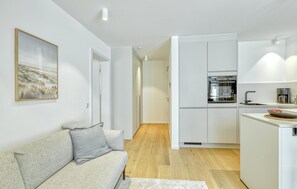 A modern kitchen with white cabinets, a built-in oven, and a coffee machine.