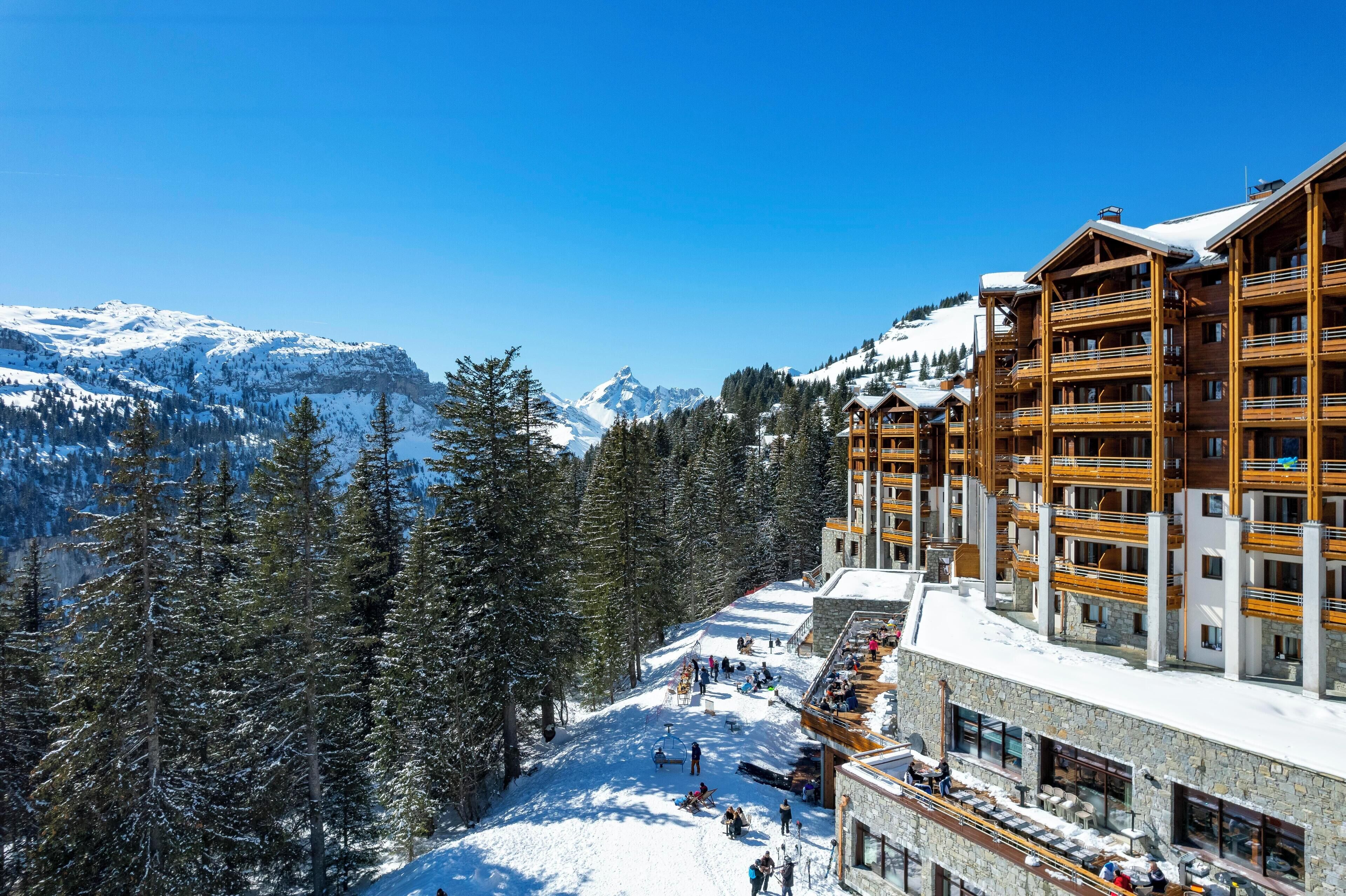 A snow-covered mountain resort with wooden buildings and a ski slope.