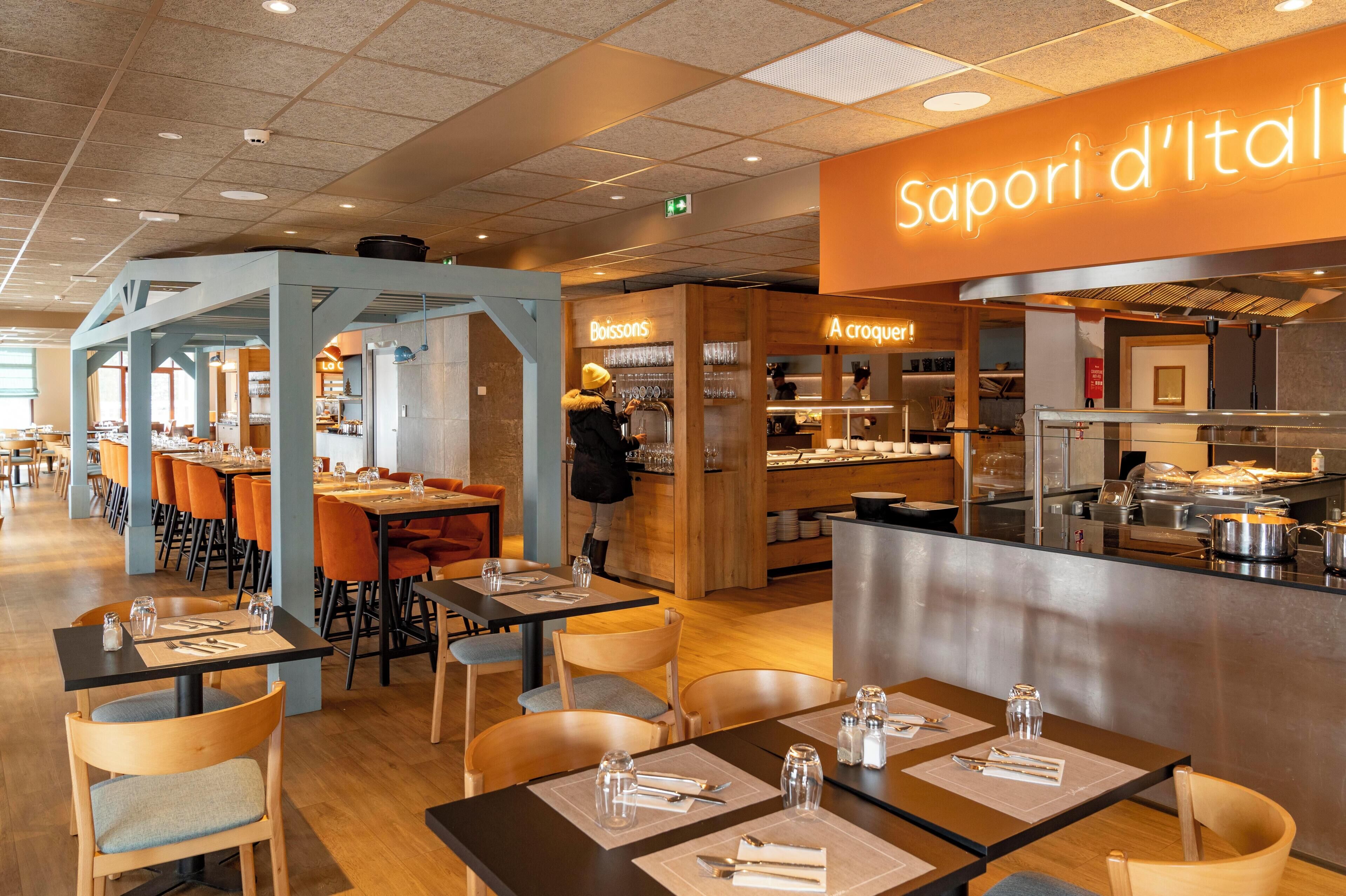 A restaurant with tables set for dining, a kitchen area, and a sign reading 'Sapori d'Italia'.