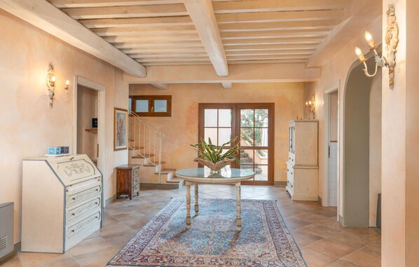 A spacious hallway with a wooden ceiling, a round glass table with a plant, and a patterned rug.