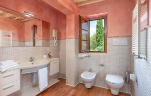 A bathroom with a sink, bidet, toilet, and a window with a view of trees. - 6 bedroom nice home in Grosseto (Grosseto)