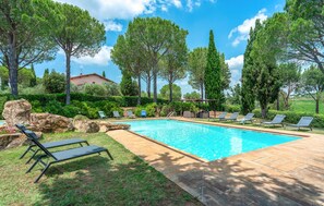 A swimming pool with lounge chairs, surrounded by trees and a stone patio. - 6 bedroom nice home in Grosseto (Grosseto)