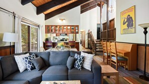 Ein modernes Wohnzimmer mit einem Ecksofa, einem Holzessttisch und einer Küche im Hintergrund.