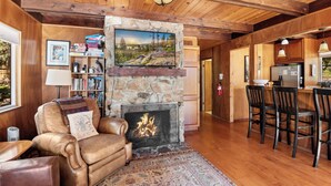 Una sala de estar acogedora con chimenea de piedra, sofá de cuero y estantería.