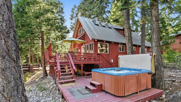 Una cabaña con jacuzzi, terraza de madera y una escalera que lleva a otra terraza.
