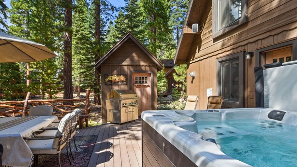 Une cabane en bois dotée d’un bain à remous, d’un espace salon extérieur et d’un coin barbecue.