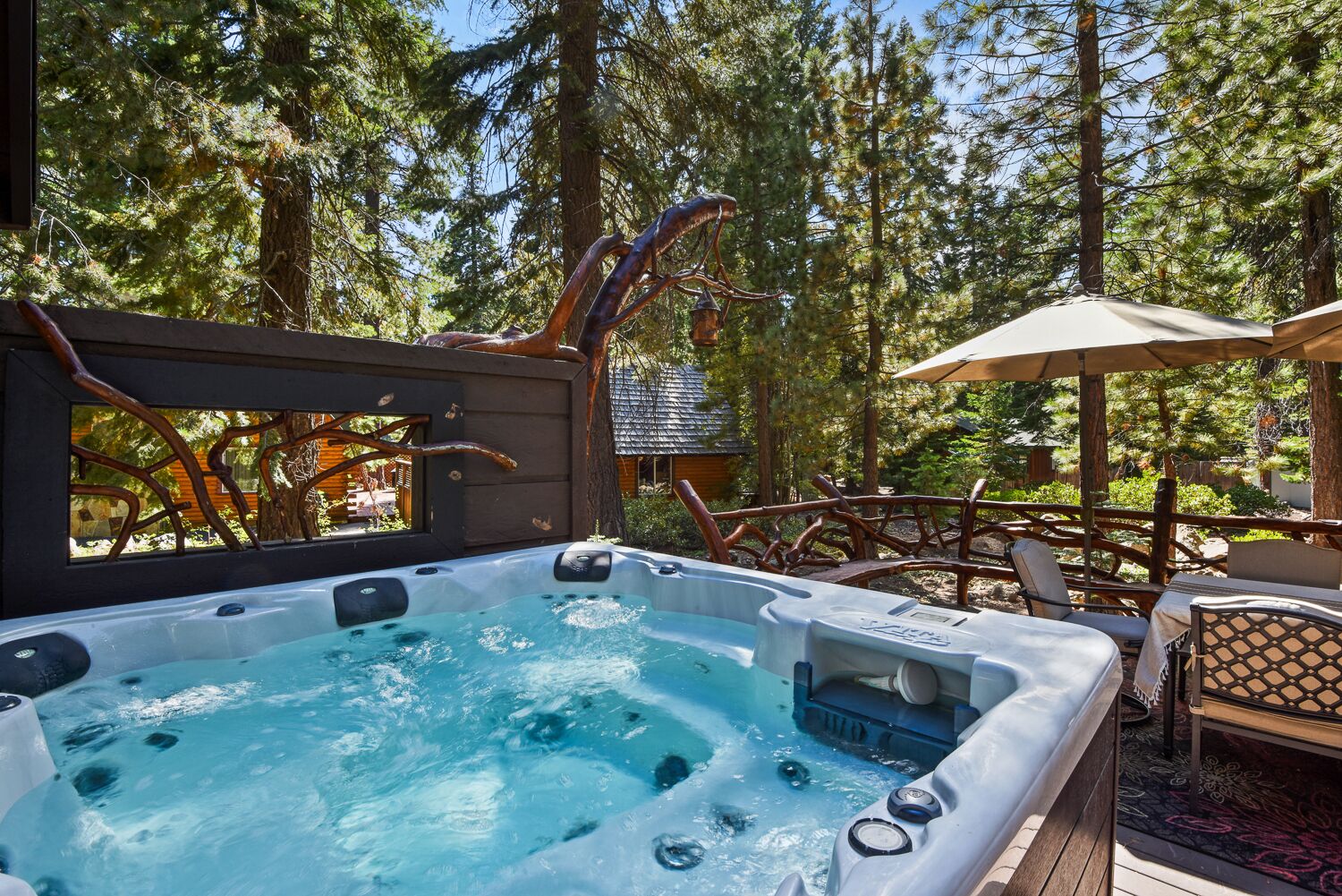 Ein Whirlpool, umgeben von einer Holzdielen-Terrasse, mit Wald im Hintergrund.