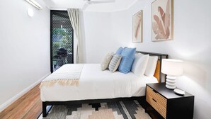 Un dormitorio moderno con cama, mesita de noche, lámpara y una obra de arte en la pared.