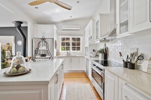 A kitchen with white cabinets, a central island, a stove, and a ceiling fan.