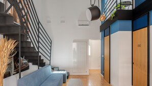 A modern interior with a staircase, a blue sofa, a small table, and a wooden cabinet. - Le Stanze di Triyah (Palermo)