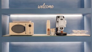 A blue wall with shelves holding a microwave, coffee machine, and a 'welcome' sign. - Le Stanze di Triyah (Palermo)