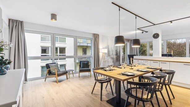 A modern dining area with a wooden table, black chairs, and pendant lighting. - GebirgsResort Winterberg (Winterberg)