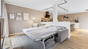 A modern bedroom with a convertible bed, a small kitchenette, and a dining area. - GebirgsResort Winterberg (Winterberg)