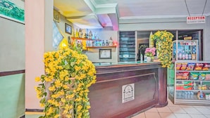 A reception area with a counter, a clock, and a sign indicating it's a business centre. - Hotel O Lie Mas Hotel (Prigen)