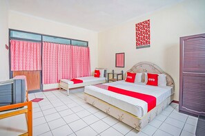 Habitación de hotel con dos camas, un escritorio y una televisión.
