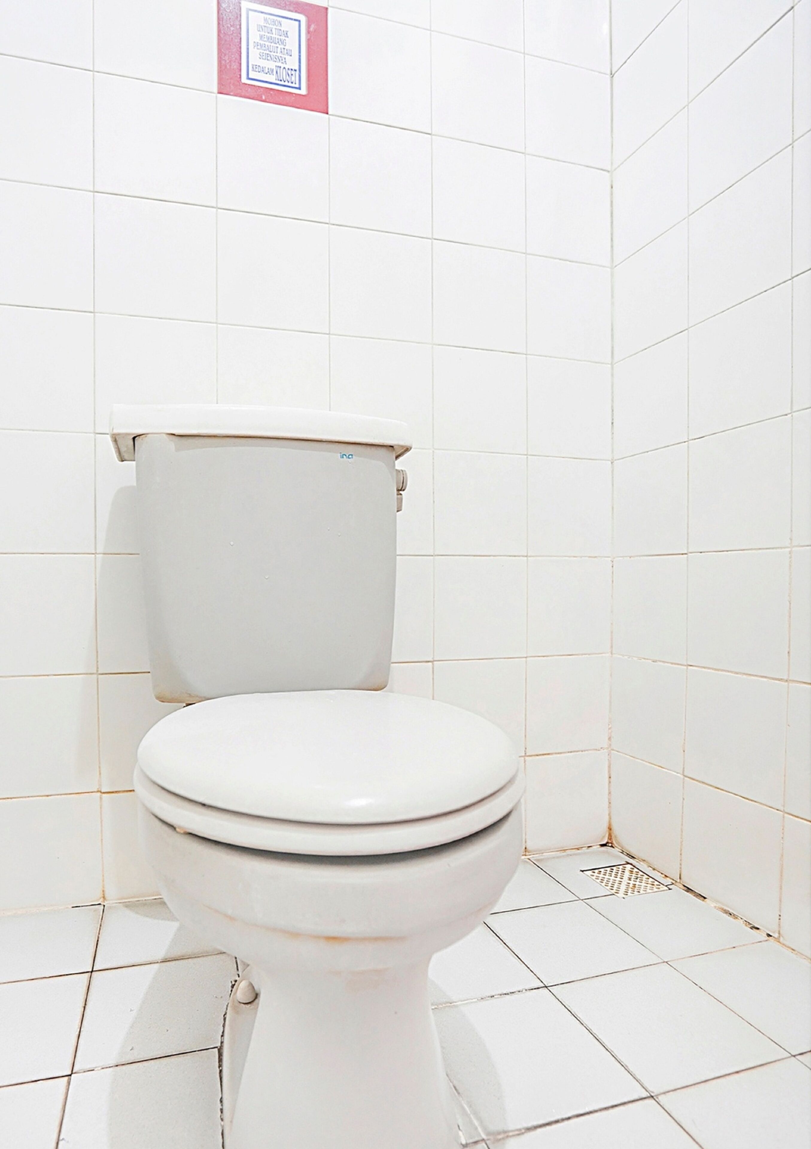 Eine weiße Toilette in einem Badezimmer mit weiß gefliesten Wänden und Boden.