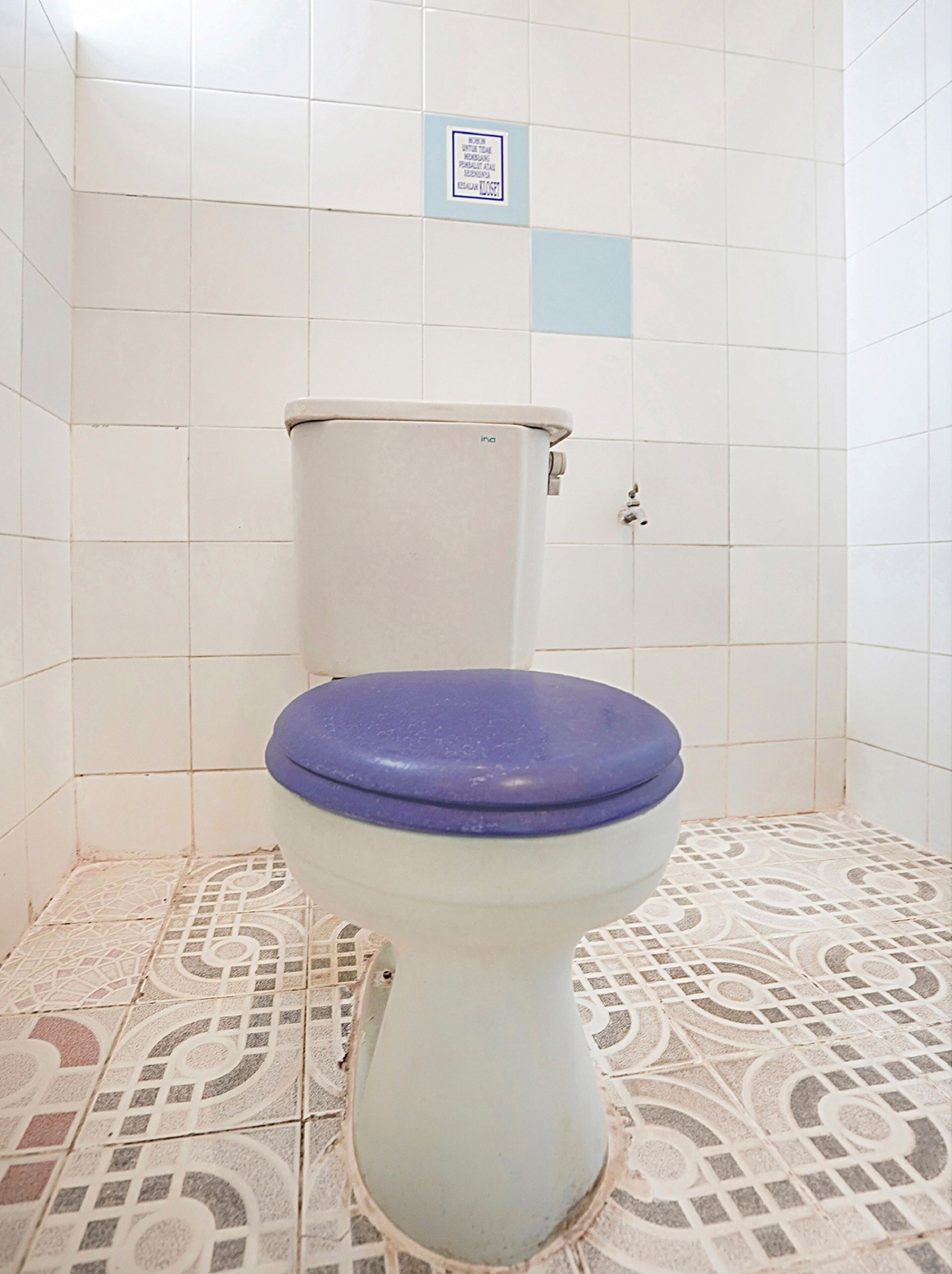 Un inodoro con asiento azul en un baño con baldosas de diseño.