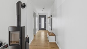 Un couloir moderne avec un poêle à bois, un banc et une porte au fond.
