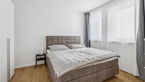 Une chambre à coucher avec un lit, une table de chevet et une fenêtre avec des rideaux.