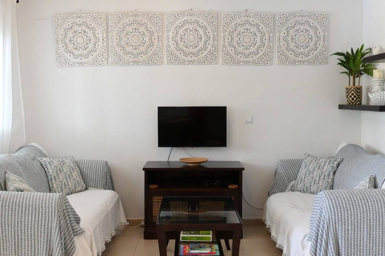 Een woonkamer met een flatscreen televisie, twee banken, een salontafel en decoratieve wandpanelen.