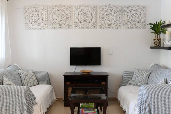 A living room with a flat-screen TV, two sofas, a coffee table, and decorative wall panels.