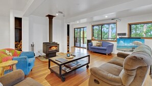 Ein geräumiges Wohnzimmer mit Kamin, einer Couch, einem Couchtisch und einem Fernseher.